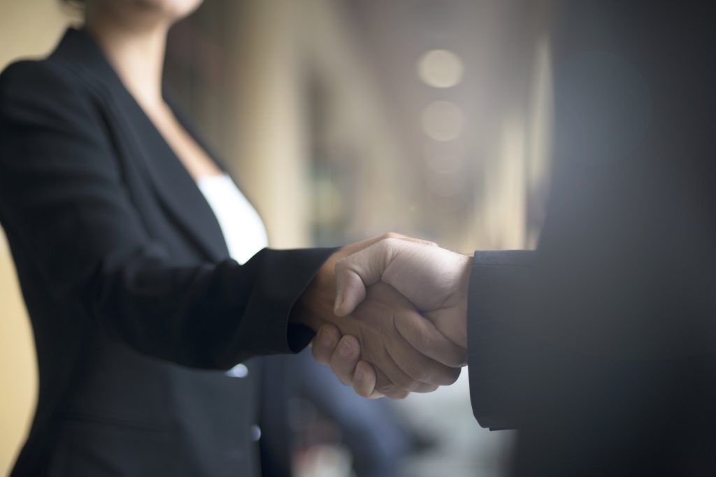Confident businesswoman shaking hands with an associate.