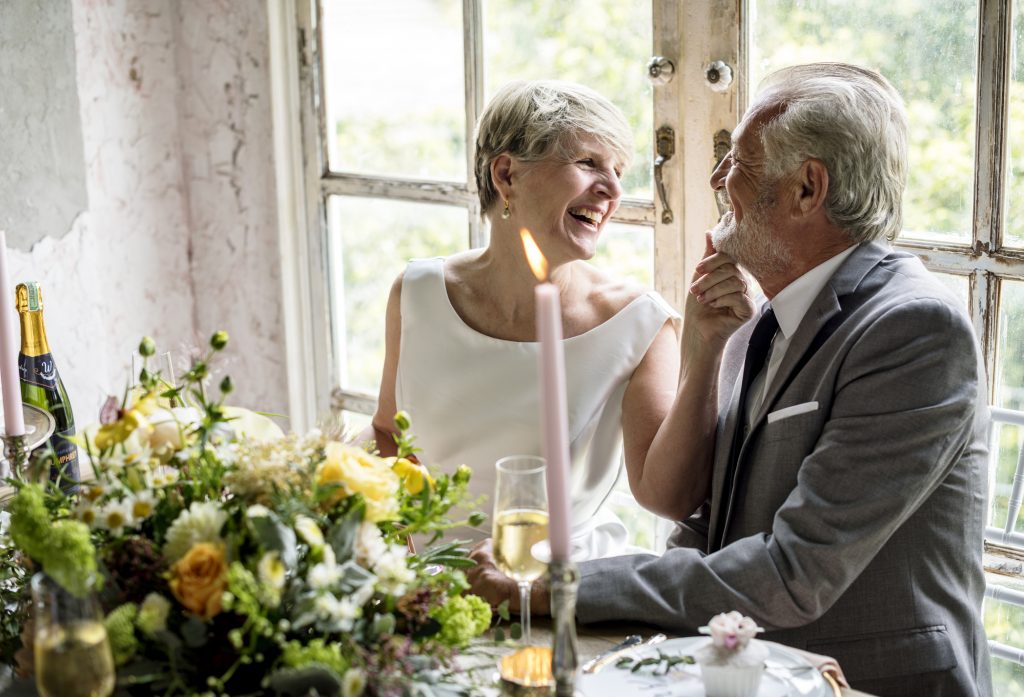 Senior couple sitting laughing together at their wedding reception.
