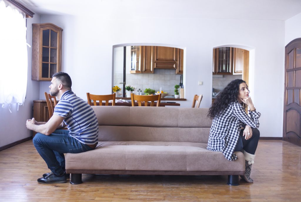 Young couple having relationship difficulties, sitting back to back at home.